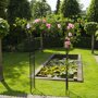 Metalen rozenboog 'New Dawn' begroeid met rozen